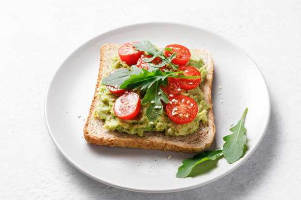 istock Avocado rye bread toast with cherry tomatoes and arugula on bright background. Healthy appetizer, breakfast, lunch or snack. Vegan food concept. Close up 1397270318