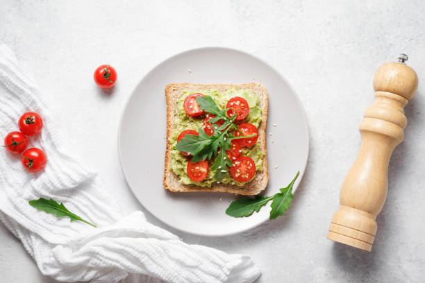 istock Avocado rye bread toast with cherry tomatoes and arugula on bright background. Healthy appetizer, breakfast, lunch or snack. Vegan food concept. Top view 1397270321