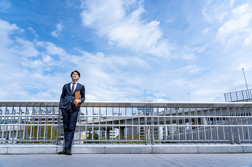 A businessman standing against the blue sky