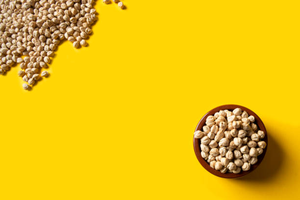 istock Uncooked chickpea beans on ceramic bowl on yellow background. This legume high in vegetal protein and perfect for vegetarian diet. 1397270703