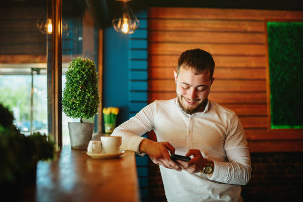 Men's lifestyle. Young man sitting in coffee shop and using a smart phone. stirring stock pictures, royalty-free photos & images