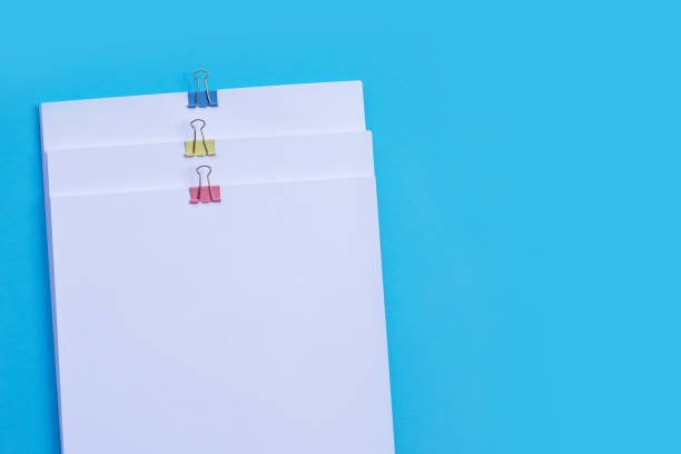 istock white paper with clip on blue background. 1397274128