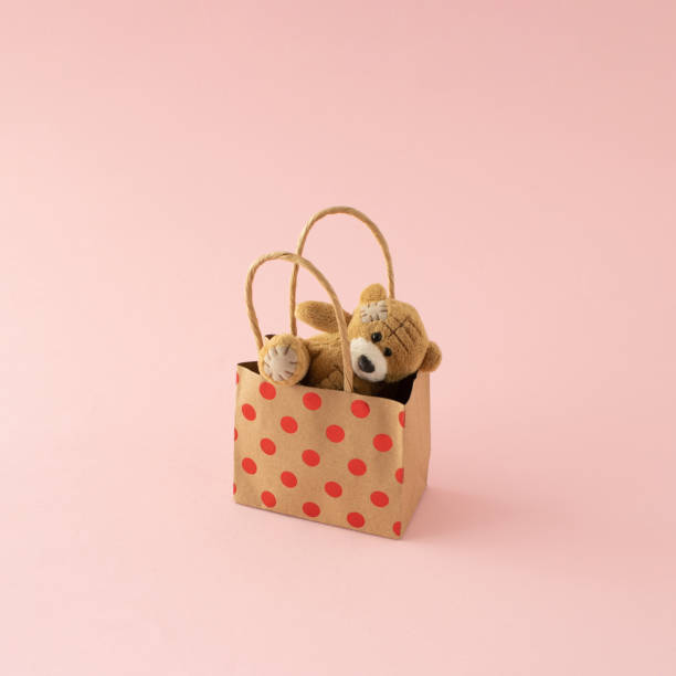 istock Buying happiness, and love. Stuffed teddy bear in gift bag. minimal creative concept on pink background. 1397276527