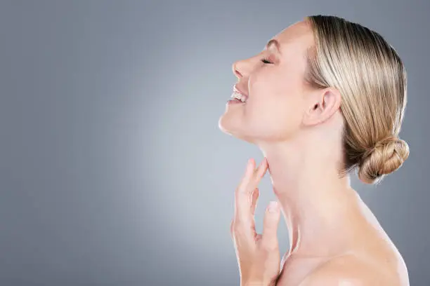 Photo of Studio shot of an attractive mature woman touching her neck against a grey background