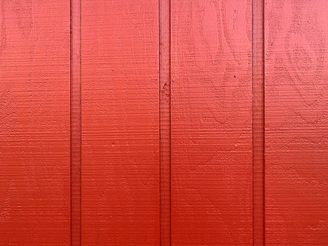 a red painted wall fence wood boards siding fresh paint maroon stain cabin house