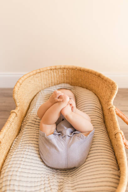 A 20 Week Old Baby Boy Holding Onto His Feet While Laying in a Cozy Gauzy Cotton Blanket in a Seagrass Moses Basket A 20 Week Old Baby Boy's Feet With 12 Toes Laying in a Cozy Gauzy Cotton Blanket in a Seagrass Moses Basket. moses basket stock pictures, royalty-free photos & images