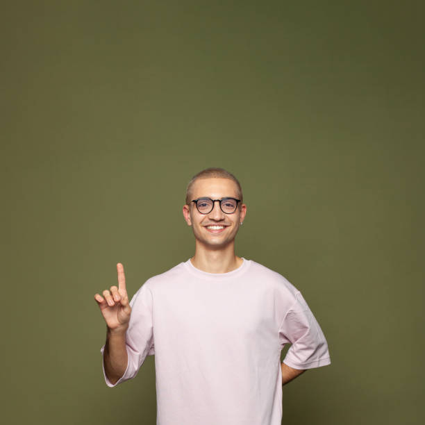 istock Young happy man student pointing up at copy space on green background 1397291992