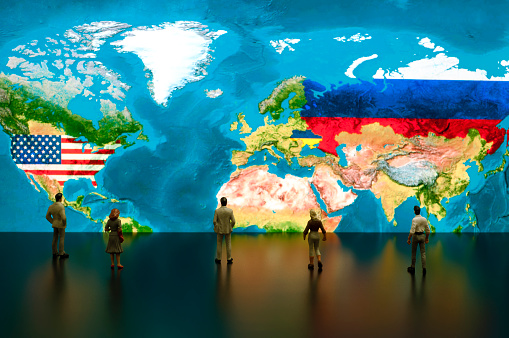 Businessman/politician figurines examine satellite view USA, Ukraine and Russia maps.