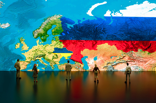Businessman/politician figurines examine satellite view Ukraine and Russia maps.