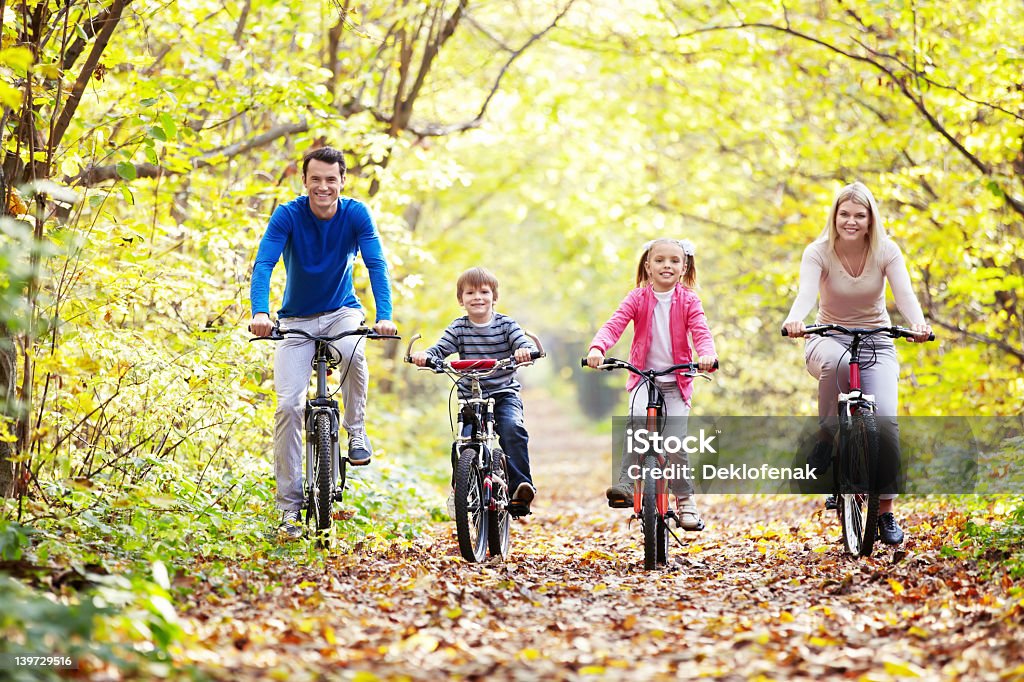 Family riding bikes through leaves The family in the park on bicycles 20-29 Years Stock Photo