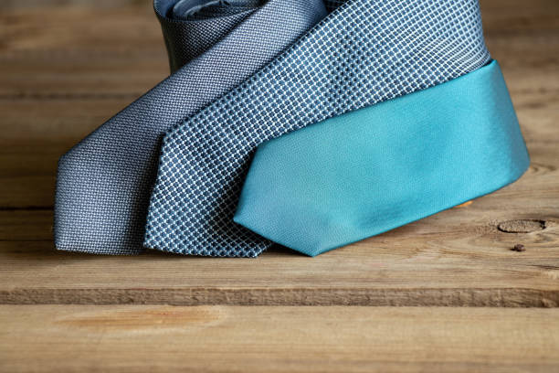 Three blue ties lie on a wooden table, different men's ties close-up