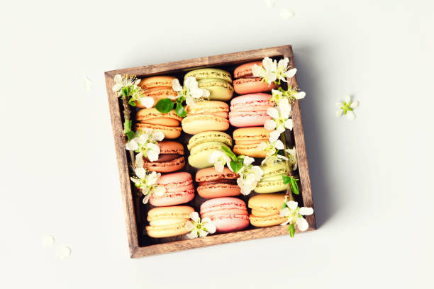 French Macaroons in wooden box with spring flowers flat lay