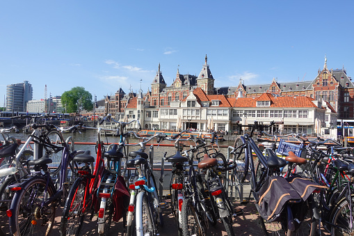 Amsterdam, the Netherlands, May 14, 2022 Lots of city bikes against the backdrop of bright rooftops. City with bike paths and sea channels.