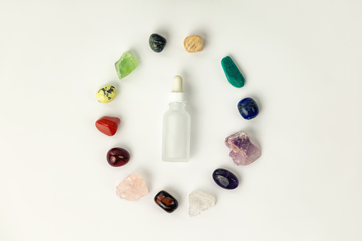 Set of healing gemstones crystals and glass bottle for making elixir in white background, top view. Crystal therapy concept