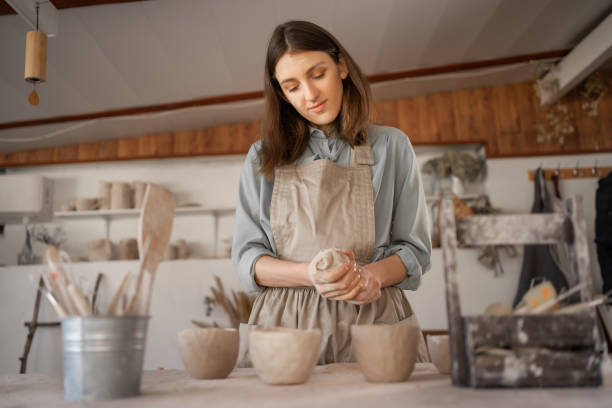 istock female artisan concentrated on modeling jug from raw clay while pottery lesson or workshop in creative studio. Woman ceramic business owner making craft for sale in handmade potter retail store 1397311296