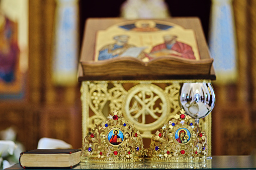 Two wedding crowns and a cup of vine on a table in orthodox church