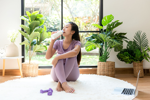 Young people girl  fitness gym for body slim. Healthy lifestyle young woman drinking milk after exercise fitness gym for body slim at living room on line.  Fitness instructor exercising the fitness. Diet and Healthy sport Concept