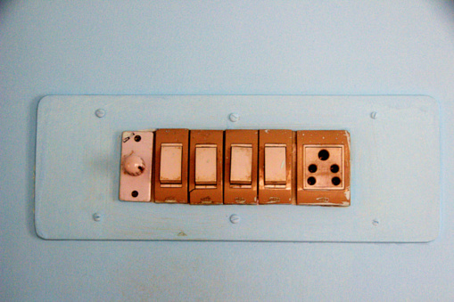 View of painted panel containing electrical switches and plug socket