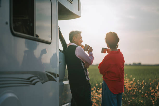 Asian chinese senior couple resting in front motor home campervan coffee break beside rice paddy field during sunset Asian chinese senior couple resting in front motor home campervan coffee break beside rice paddy field during sunset rv travel stock pictures, royalty-free photos & images