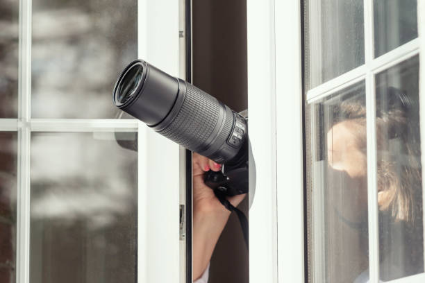 istock Private detective with spying zoom lens camera taking picture through open window. Close 