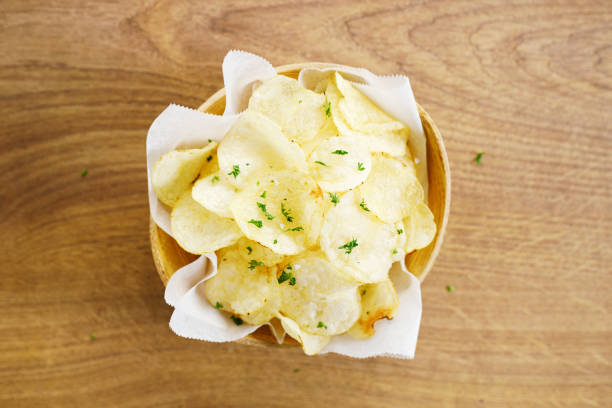 Fresh homemade potato chips with parsley in wooden bowl. Closeup.