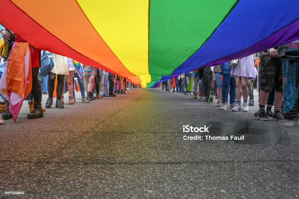 Under a LGBT Pride Flag Under a LGBT Pride Flag with the legs of people carrying the flag Protest Stock Photo