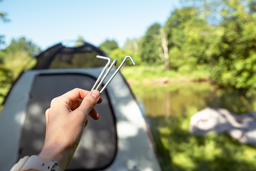Aluminum stakes for the installation of a tourist tent in the hand close-up. Lightweight equipment for tourism. Outdoor activities, assembly instructions, domestic ecotourism. Copy space