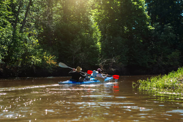 coppia uomo e donna in famiglia kayak viaggio in barca a remi sul fiume, un'escursione in acqua, un'avventura estiva. turismo ecologico ed estremo, stile di vita attivo e sano - canoeing people traveling camping couple foto e immagini stock