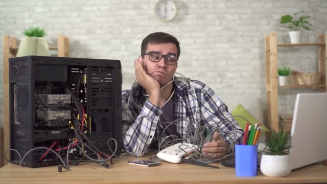 Funny discouraged man in glasses in wires with a router in his hands has problems with the Internet