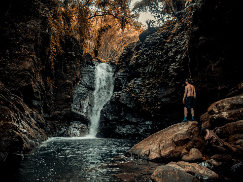 Hiker with back turned facing Meihua waterfall in the mountains of Hsinchu County, Taiwan