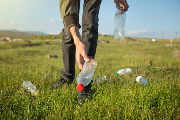 istock Man picks up a plastic bottles from grass park. 1397333492