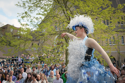 Genk. Limburg -Belgium 01-05-2022. Artists in costumes on the city street. Girl on stilts in a dress made of plastic bottles. O-parade in Genk