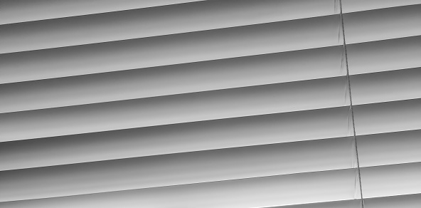 Abstraction. Striped background. closed blinds. Black and white photo. Striped background and one thin transverse strip on one side. The play of light and shadow is gray tones.