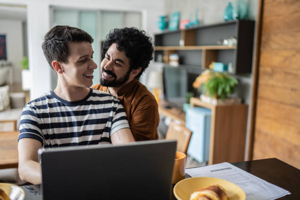 istock Gay couple using laptop and embracing during breakfast at home 1397340792