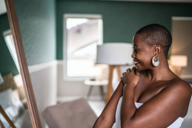 Woman wearing a towel applying moisturizer