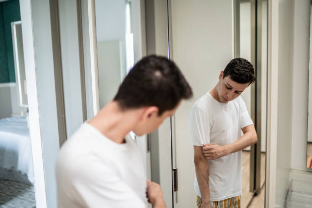 Young man getting dressed and looking in the mirror at home
