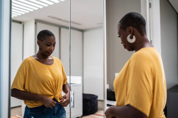 自宅で鏡を見て服をアレンジする中途半端な大人の女性 - 試着室 ストックフォトと画像