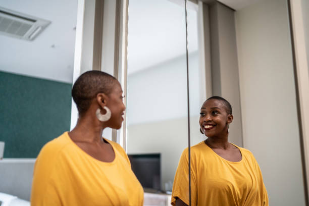 mid adult woman looking in the mirror at home - mirror vanity women looking imagens e fotografias de stock