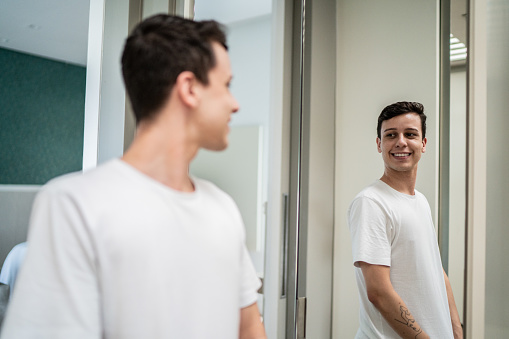 Young man looking in the mirror at home