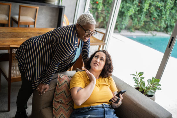istock Female friends talking and using the mobile phone at home 1397341834