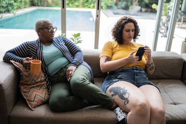 istock Friends relaxing on sofa and using mobile phone at home 1397342108