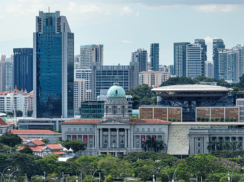 Singapore, Singapore - March 1, 2016: Granite sign and Parliament house building in Singapore. Skyline with skyscrapers od Downtown core on the background