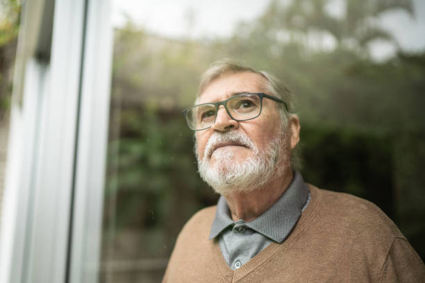istock Contemplative senior man looking through window at home 1397342770