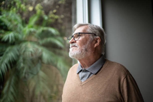 istock Contemplative senior man looking through window at home 1397342771