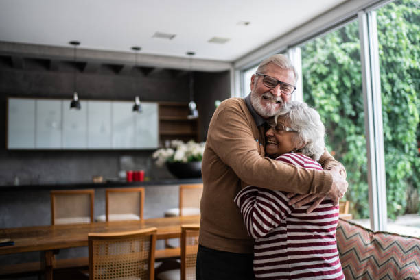 un couple de personnes âgées s’étreignant à la maison - people cheerful happiness candid photos et images de collection