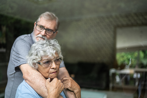 Worried contemplative senior couple at home