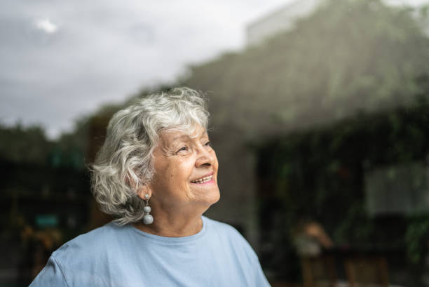 istock Senior woman looking through the window at home 1397343619
