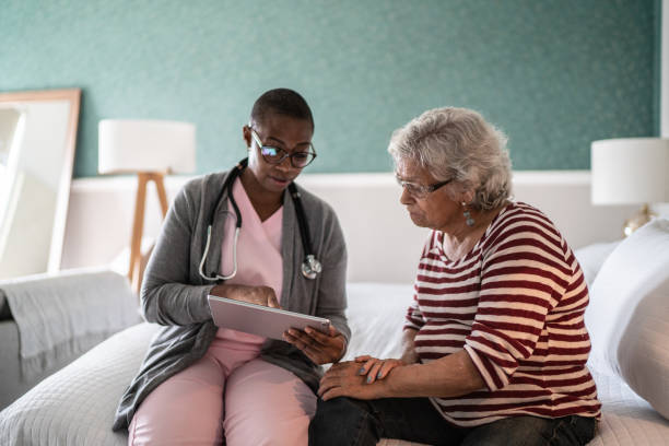 lekarz rozmawia ze starszą kobietą w sypialni - community outreach aging process human age retirement zdjęcia i obrazy z banku zdjęć