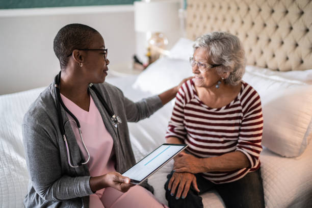 medico che parla con una donna anziana in camera da letto - senior adult nursing home assisted living talking foto e immagini stock