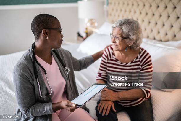 Doctor talking to a senior woman in the bedroom